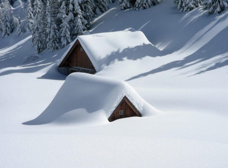 Neve che ricopre delle casette di legno in montagna.